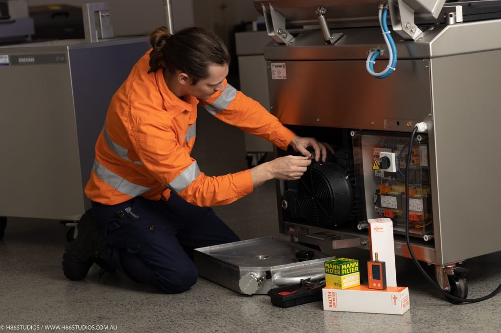 A technician performing maintenance on a Henkelman machine.