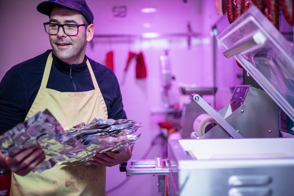 A butcher holding vacuum sealed packages of high liquid content meat.